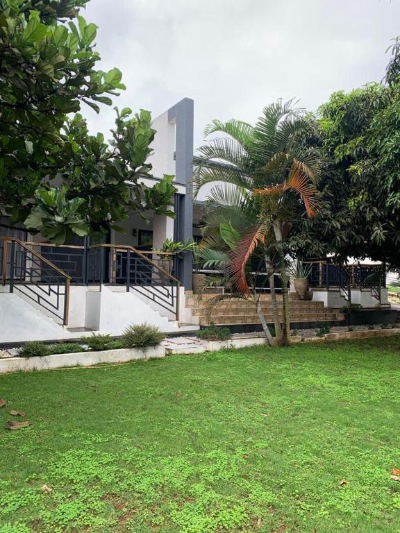 a building with a palm tree in front of a yard at Bella Vida Hotel apartment in Kigali
