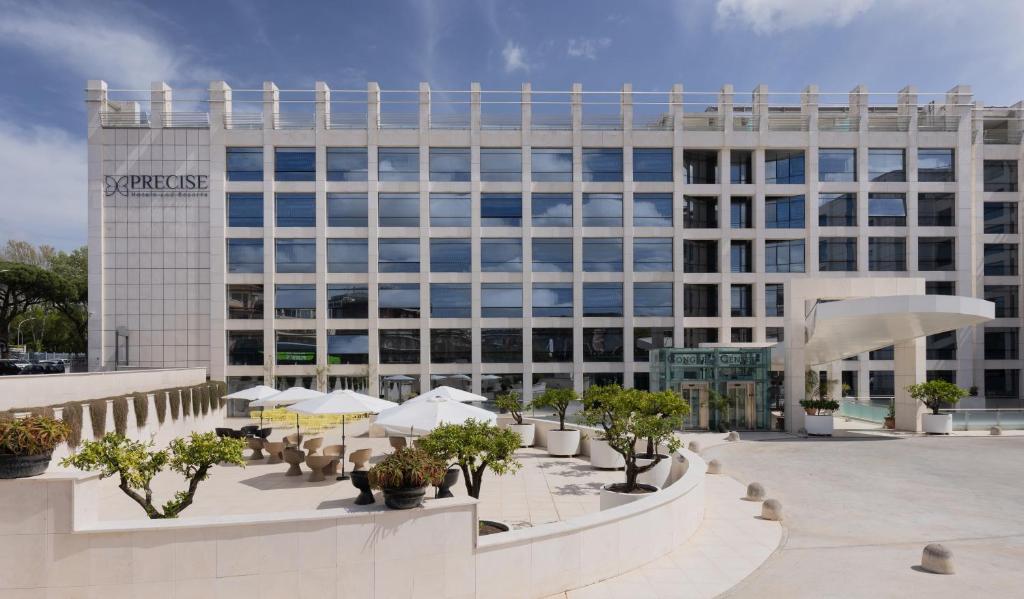 un gran edificio blanco con árboles delante de él en Precise House Mantegna Roma en Roma