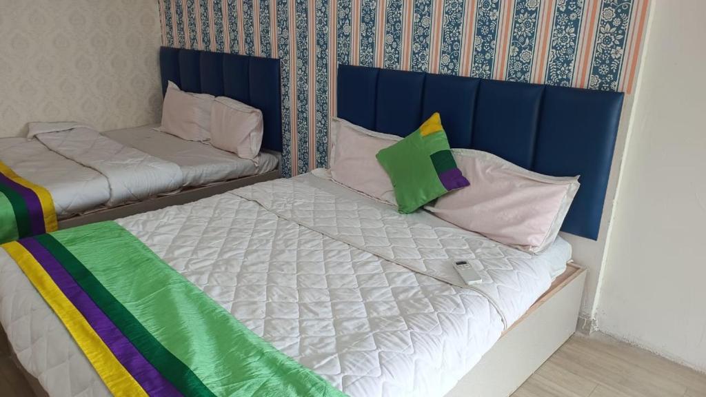 two beds with colorful pillows on them in a room at Hotel Sawariya in Ahmedabad