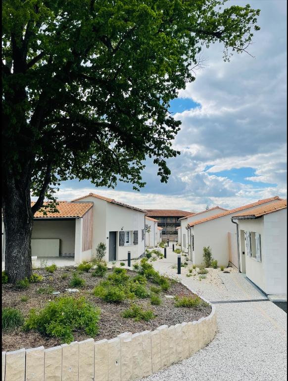 une rangée de bâtiments blancs avec un arbre dans l'établissement Résidence Grand Tilleul, à Jonzac