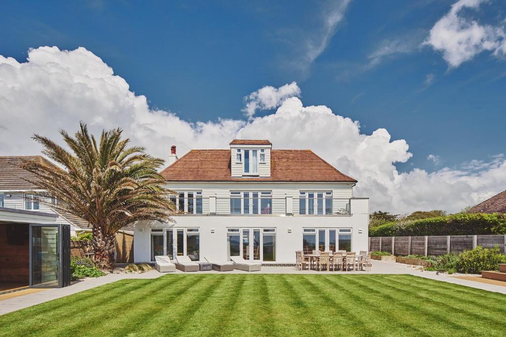 a large white house with a large yard at Sun Beach House in Middleton-on-Sea