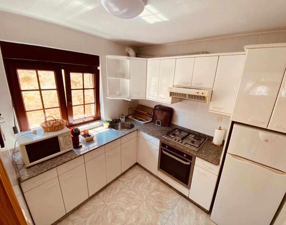a kitchen with white cabinets and a stove top oven at Casa entre el Mar y la Montaña in Caravia