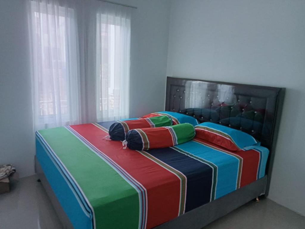 een bed met kleurrijke dekens en kussens erop bij VILLA DUMA ORCHID Cipanas in Cipanas