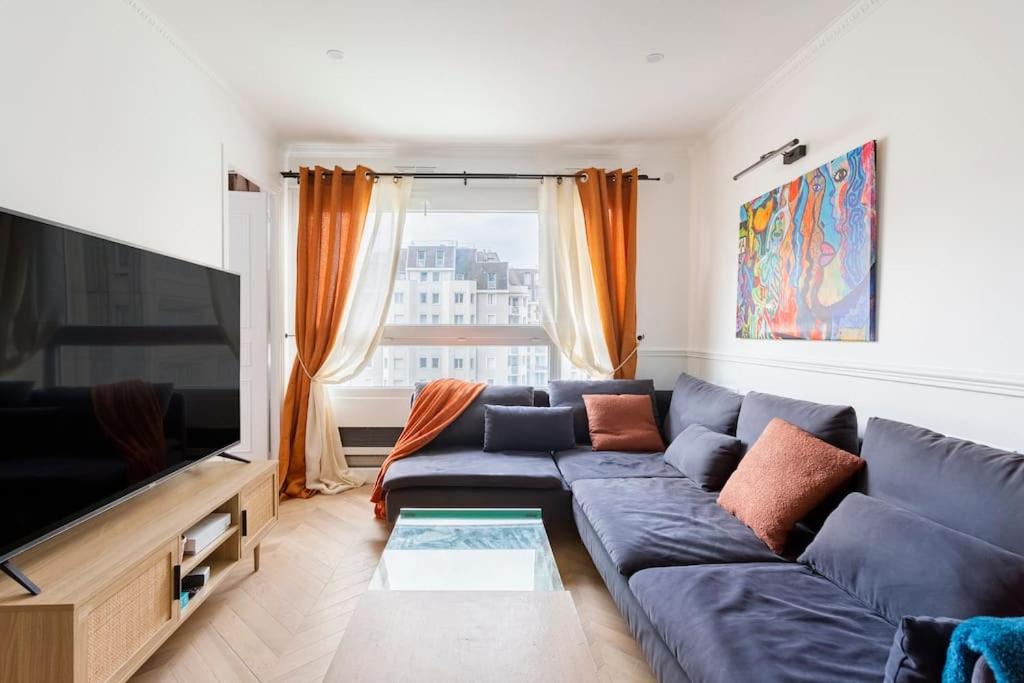 un salon avec un canapé bleu et une télévision à écran plat dans l'établissement Cosy Haussmanian apartment, à Paris
