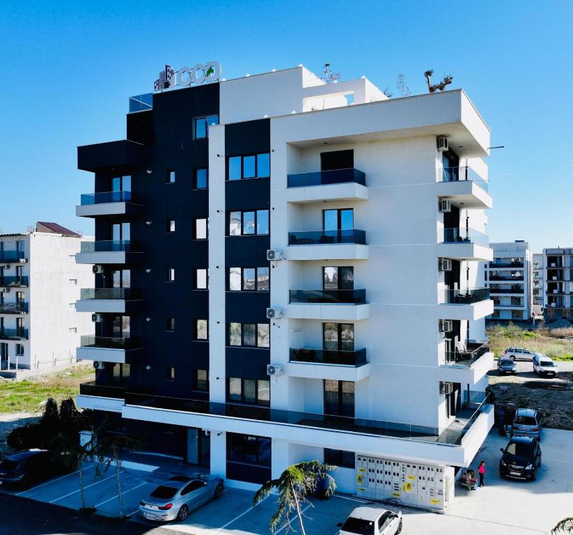 a black and white building with cars parked in a parking lot at Promenada Apartments in Năvodari