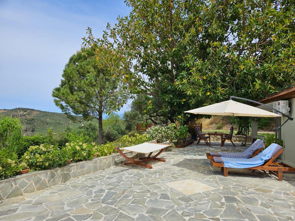 une terrasse avec une table, des chaises et un parasol dans l'établissement Kymanemi Zakynthos Cottage House, à Áno Yerakaríon