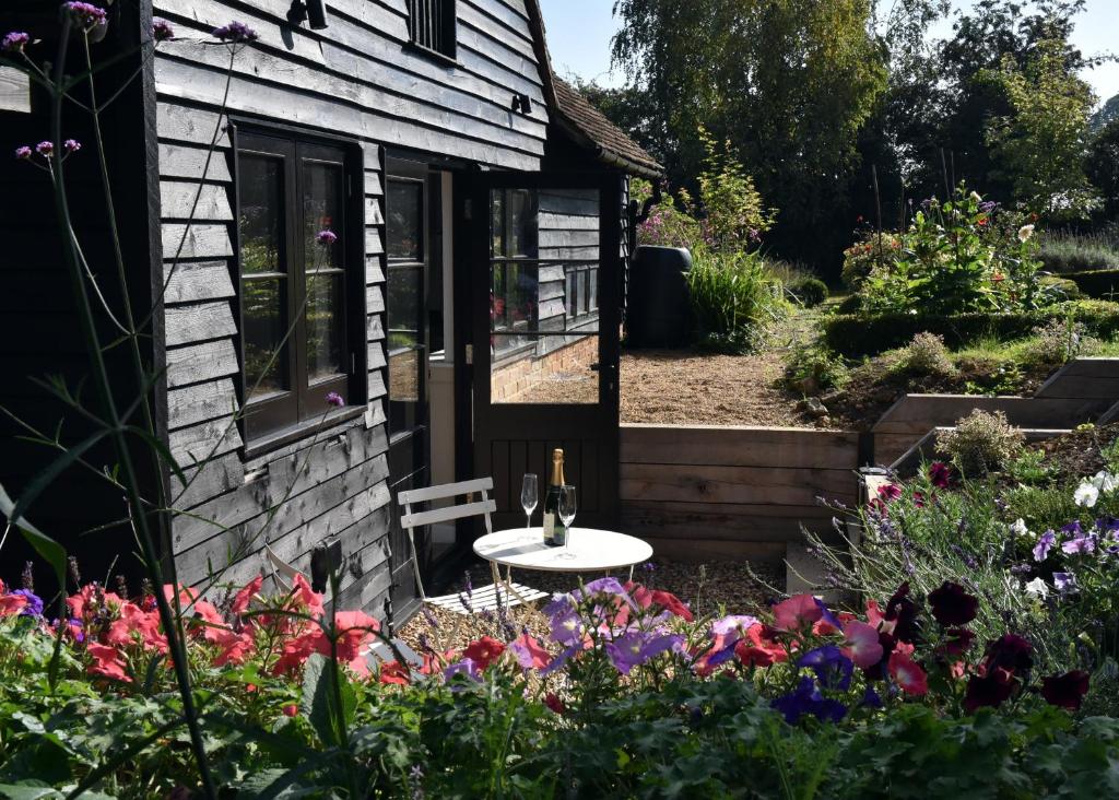 a garden outside a house with a table and flowers at Cherry Orchard Farm in Maidstone
