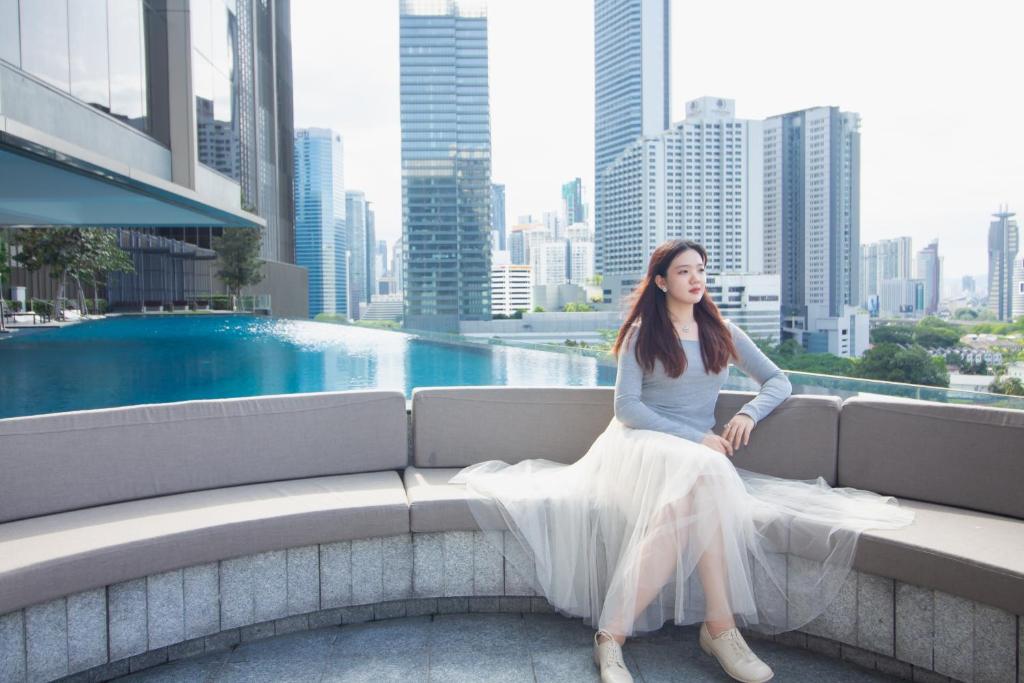 a woman sitting on a ledge with a view of a city at PAVILION EMBASSY KLCC By ELITE HOST in Kuala Lumpur