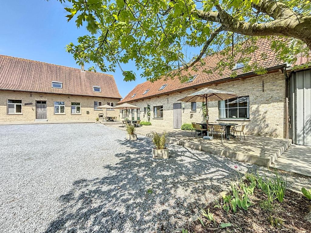 a building with a table and an umbrella in front of it at De Eikhoeve - Alveringem in Alveringem
