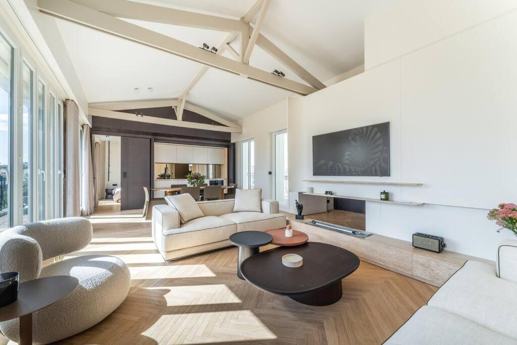Il comprend un salon doté d'un mobilier blanc et d'une télévision. dans l'établissement Haussman Palace Appartment, à Paris