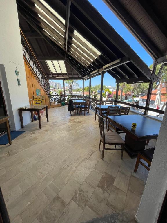 a large room with tables and chairs and windows at Bedesten Pansiyon in Çeşme