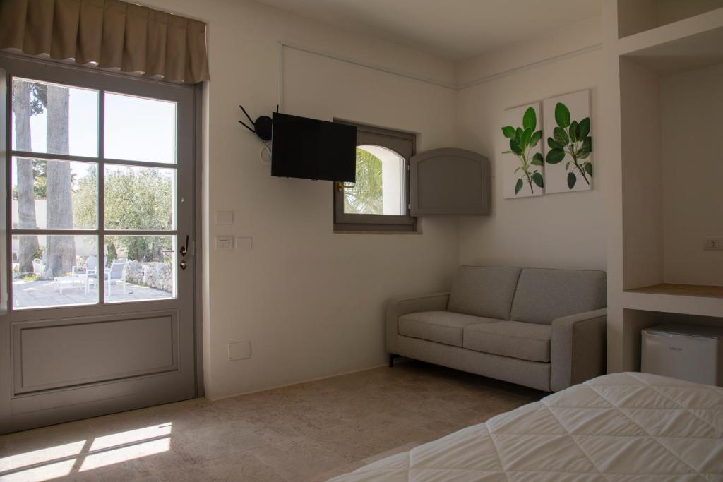 um quarto com uma cama, um sofá e uma janela em Masseria Celentano Relais & Agriturismo em San Severo