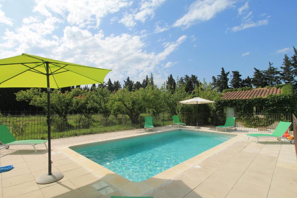 - une piscine avec un parasol jaune et des chaises dans l'établissement Clos Christol B, à Graveson