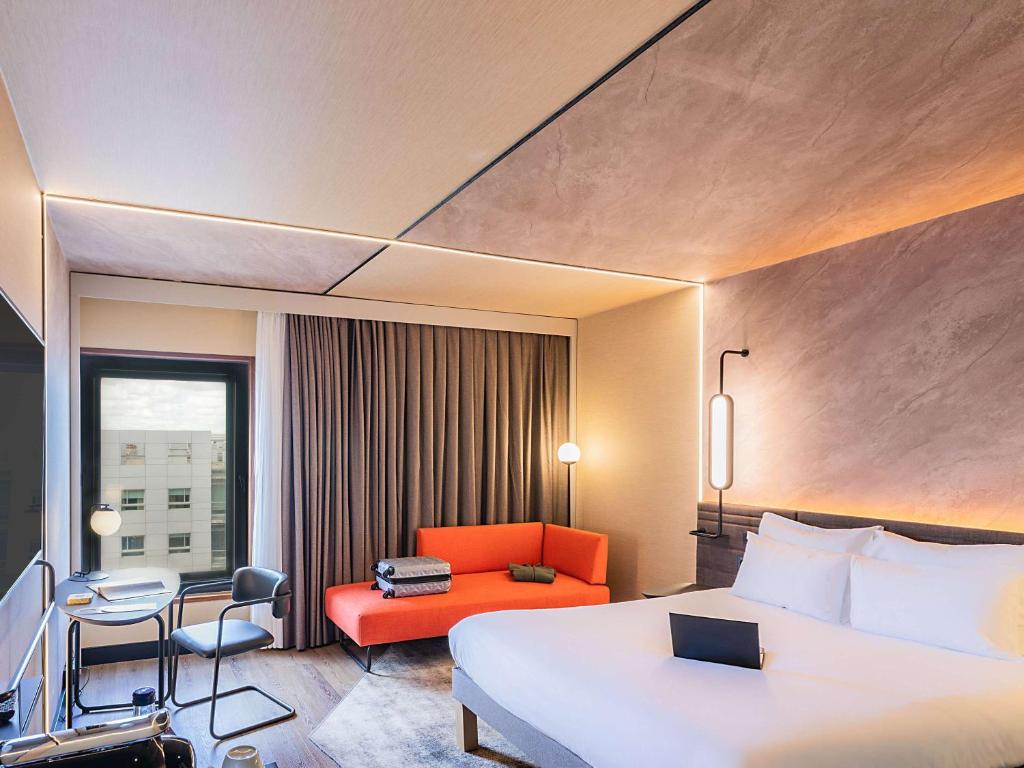 una camera d'albergo con letto, sedia e scrivania di Novotel Lisboa a Lisbona