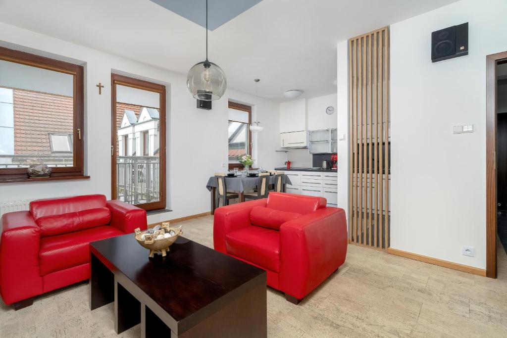 een woonkamer met 2 rode stoelen en een tafel bij Apartament nad Wartą z Parkingiem w Poznaniu by Renters in Poznań