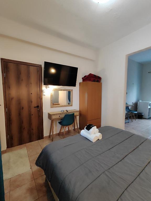 a bedroom with a bed and a desk and a television at Poseidon Rooms in Kala Nera