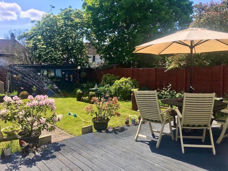 a patio with two chairs and a table with an umbrella at Large One Bedroom House near Twickenham stadium in Isleworth