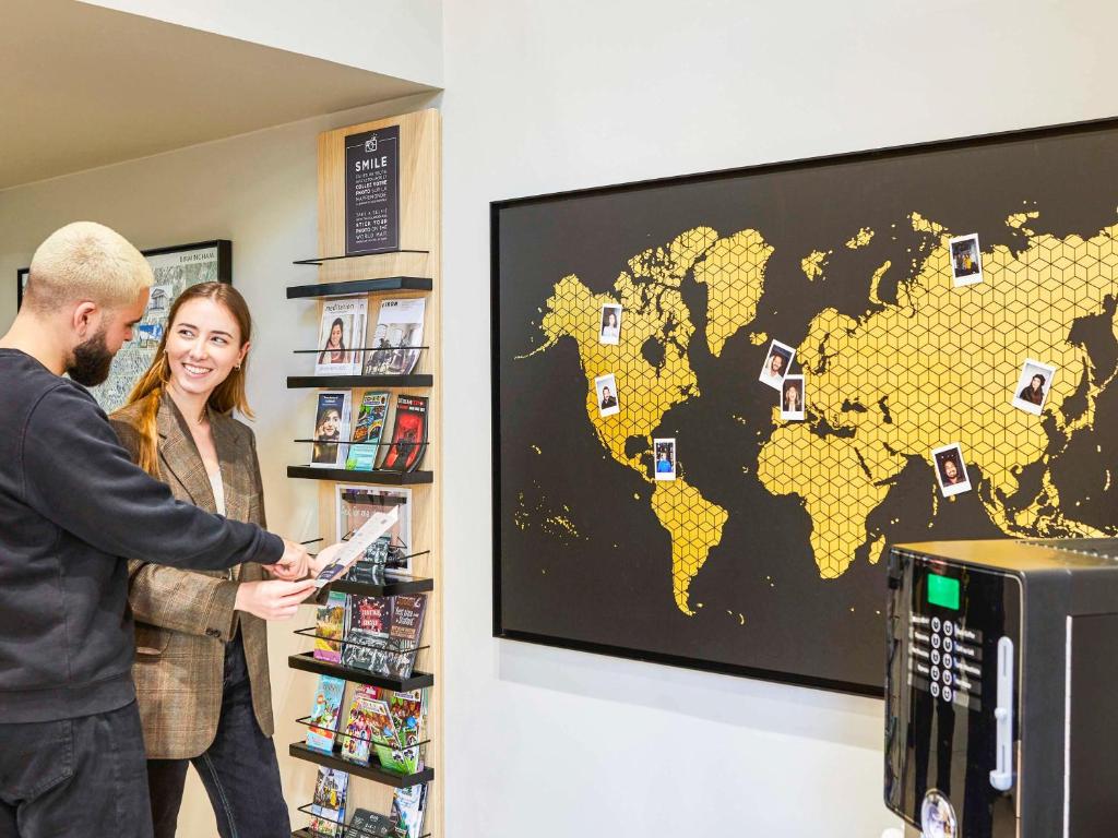 a man and woman standing in a store with a map of the world at Aparthotel Adagio Birmingham City Centre in Birmingham