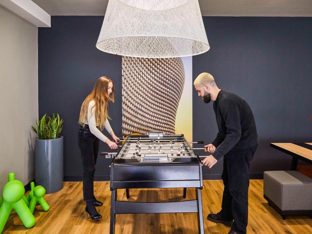 a man and a woman standing next to a giant chessboard at Aparthotel Adagio Birmingham City Centre in Birmingham
