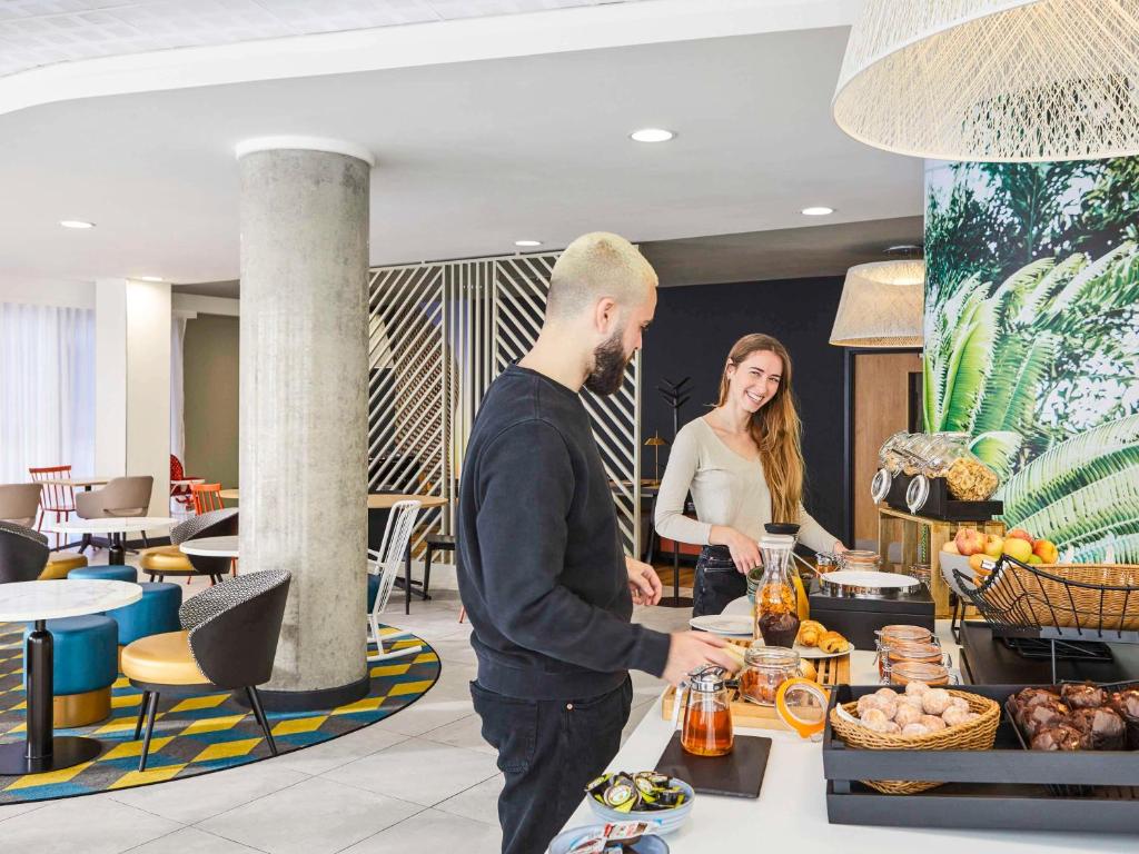 a man and a woman standing behind a counter with food at Aparthotel Adagio Birmingham City Centre in Birmingham