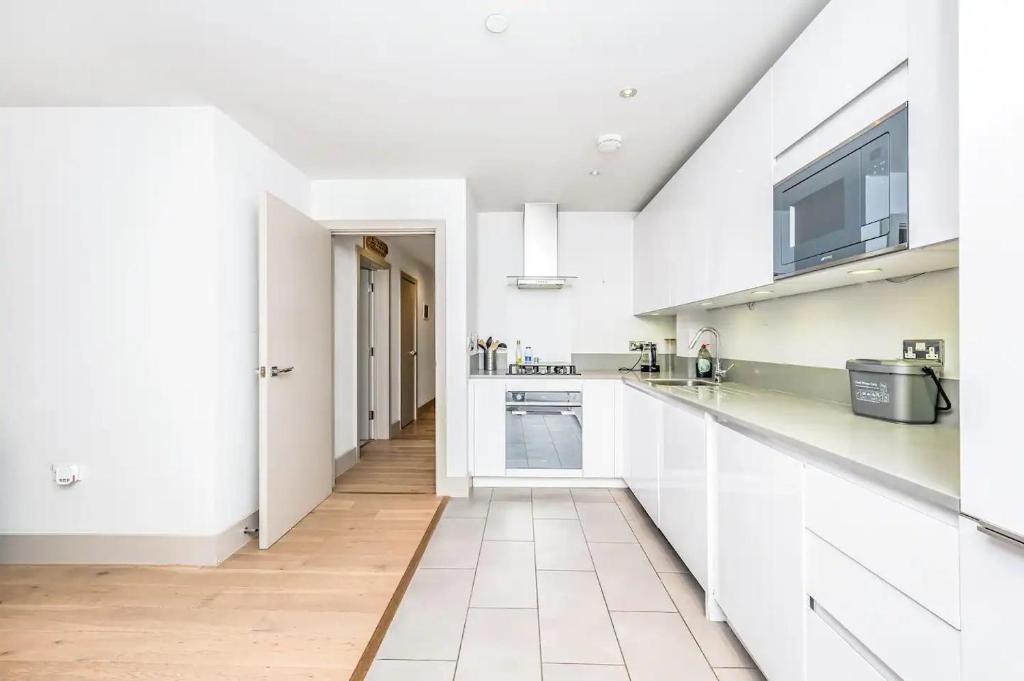 una cocina blanca con armarios blancos y fregadero en Pass the Keys Modern Home-Private Parking-Garden en Londres