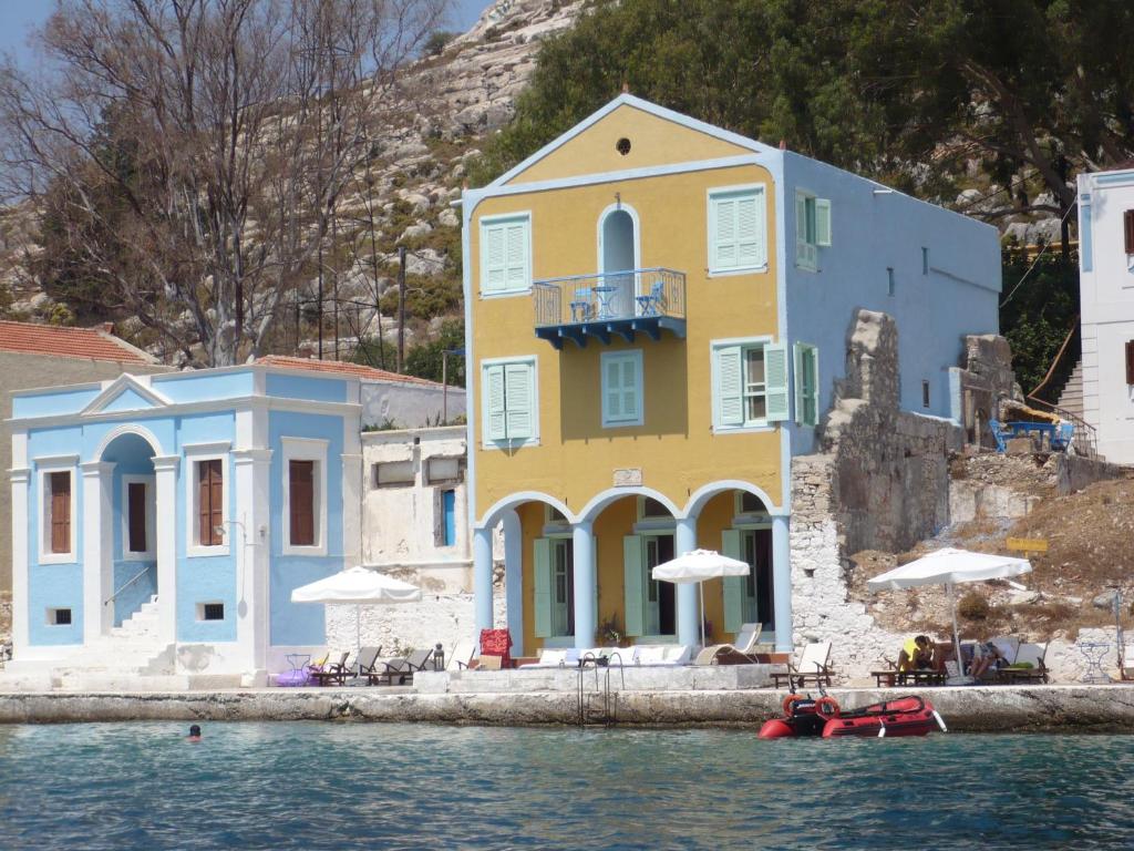 a yellow and blue building next to the water at Mediterraneo Hotel in Meyisti