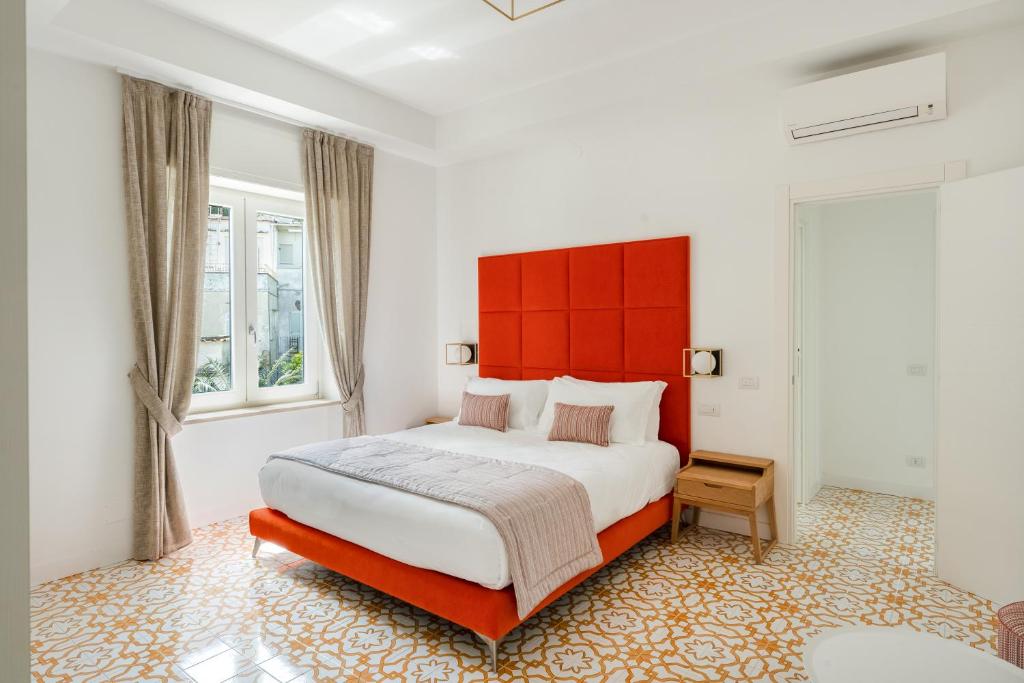 Casa Levante Luxury Apartments Capri في كابري: غرفة نوم بسرير كبير مع اللوح الأمامي الأحمر