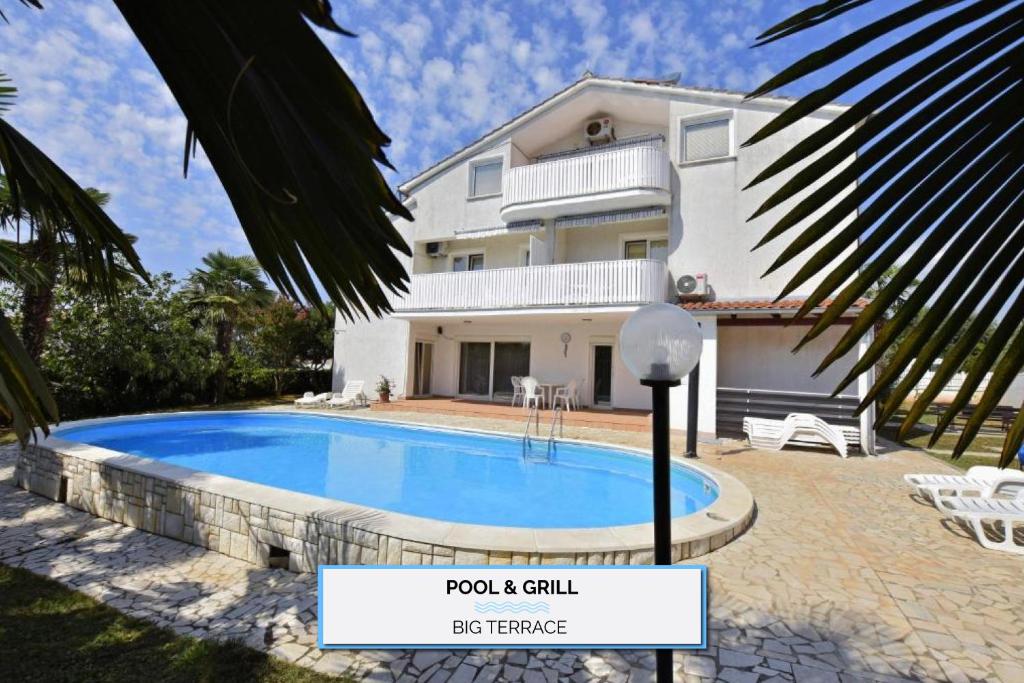a villa with a swimming pool in front of a house at Apartments Vila Marinela in Poreč