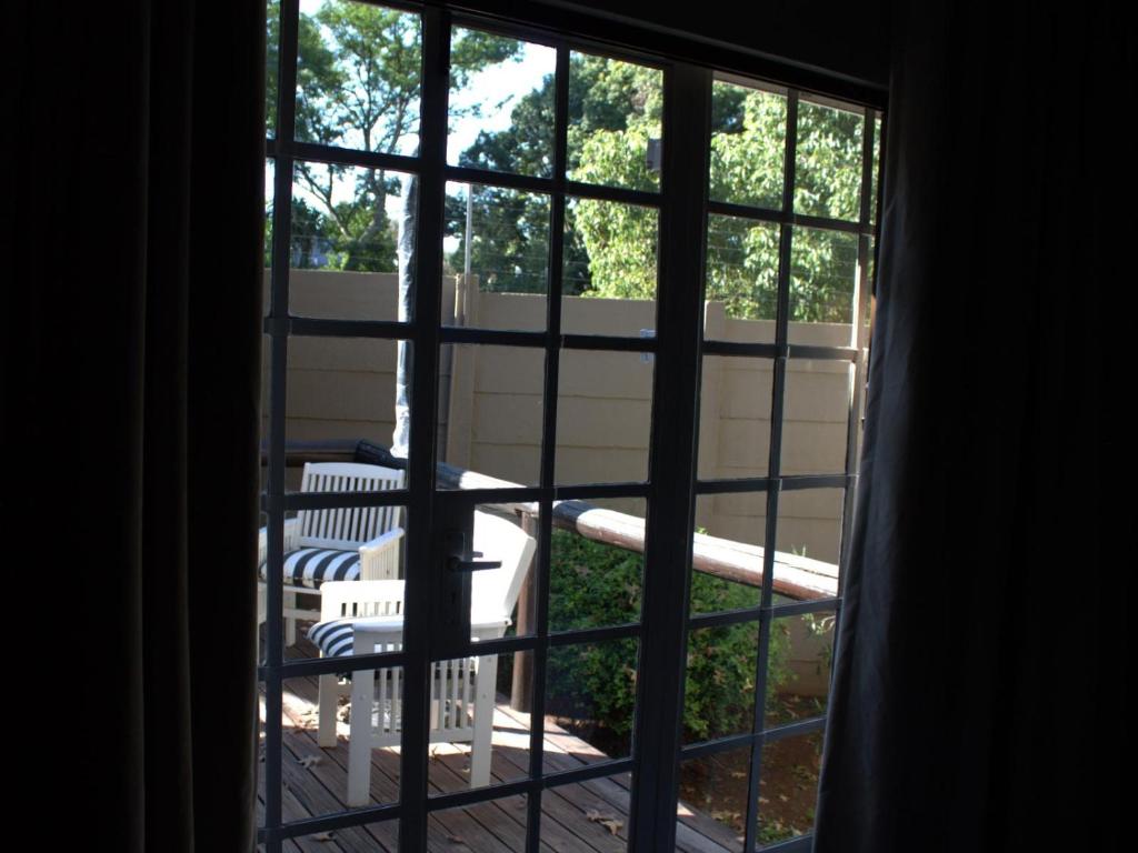 a window view of a deck with a table and chairs at Wild Tree Lodge in Benoni