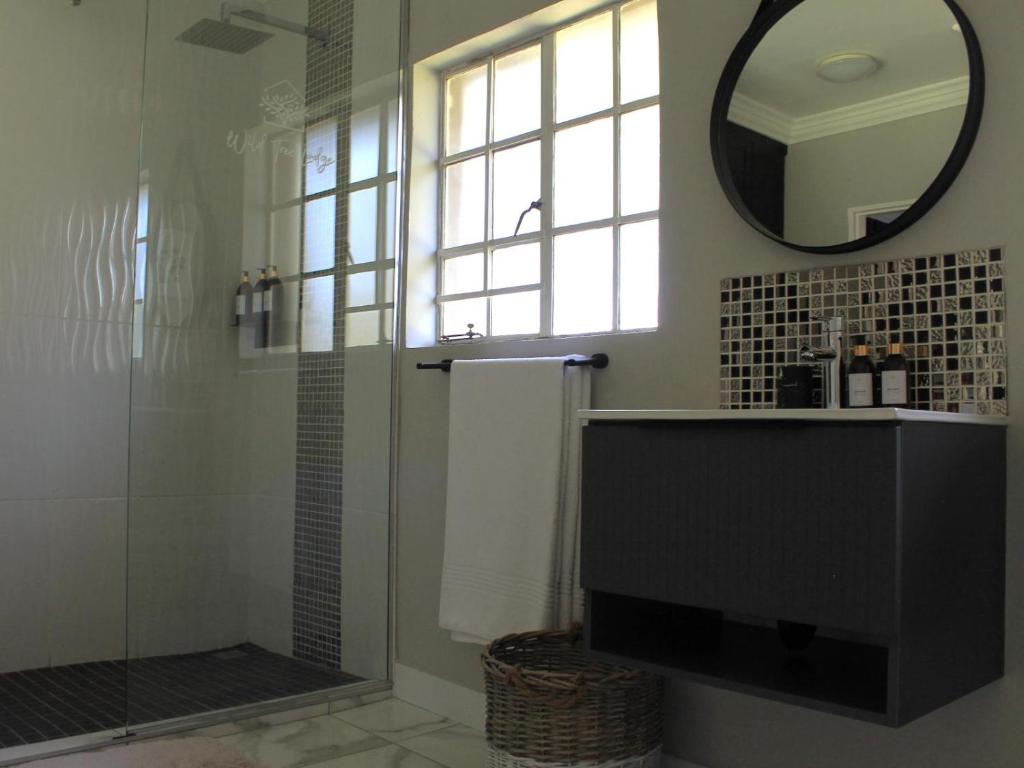 a bathroom with a shower and a sink and a mirror at Wild Tree Lodge in Benoni