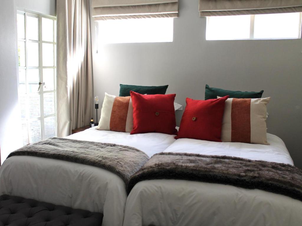 a bedroom with a large bed with red pillows at Wild Tree Lodge in Benoni