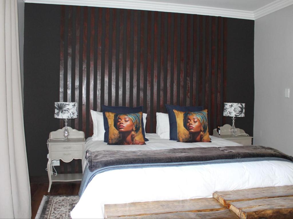a bedroom with a large bed with two women on pillows at Wild Tree Lodge in Benoni
