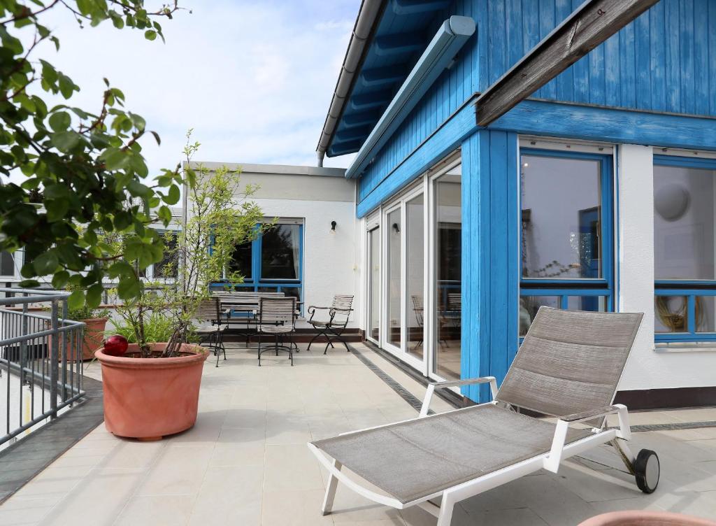 una casa blu con una sedia a dondolo su un patio di Relaxing 140m2 Holiday Home South of Munich - 25 Min to Center - Fully Equipped a Baierbrunn