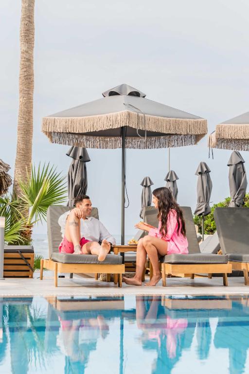 a group of people sitting on lounge chairs next to a swimming pool at Soleil Rooms and Suites in Stalís