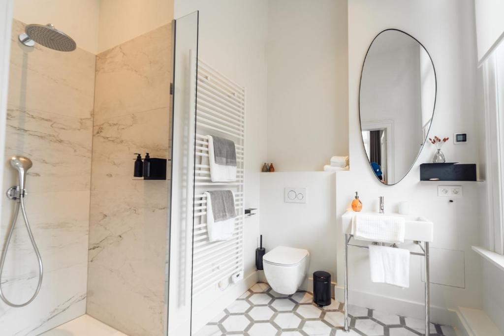 ein Bad mit einer Dusche, einem Waschbecken und einem Spiegel in der Unterkunft Luxeverblijf B&B het Wevershuis in Herentals