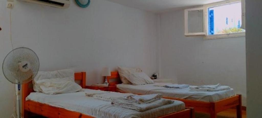 two beds in a room with a fan and a window at Καραμπεικο in Piso Livadi