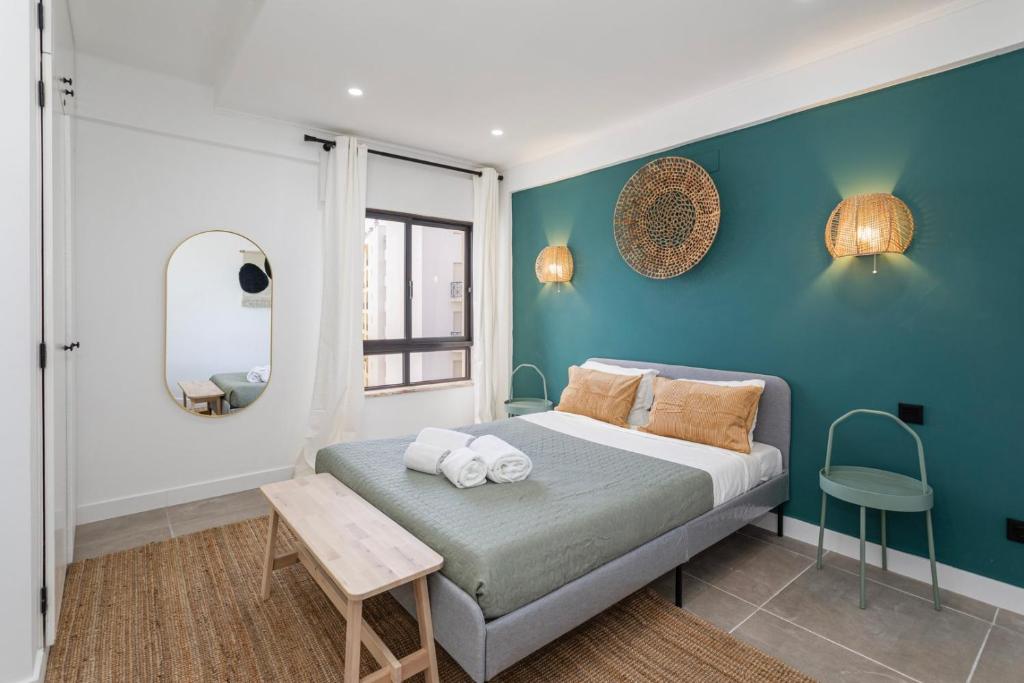 um quarto com uma cama e uma parede azul em Seashore Rosamar em Armação de Pêra