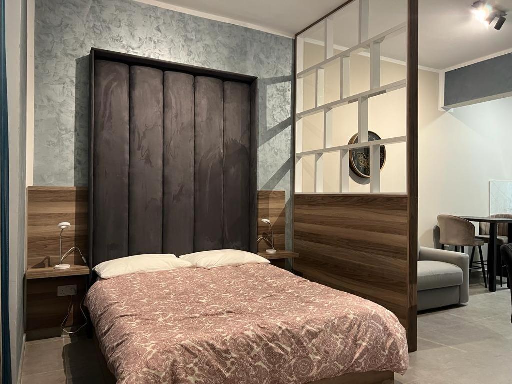 una camera con un grande letto con testiera in legno di Stresa Court Apartments a San Giuliano