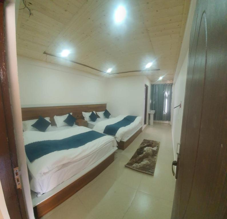 1 dormitorio con 2 camas y almohadas azules en Hotel Geeta Badrinath, en Badrīnāth