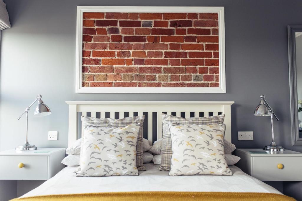 a bedroom with a brick wall and a bed with pillows at The Caledon Guest House in Cowes