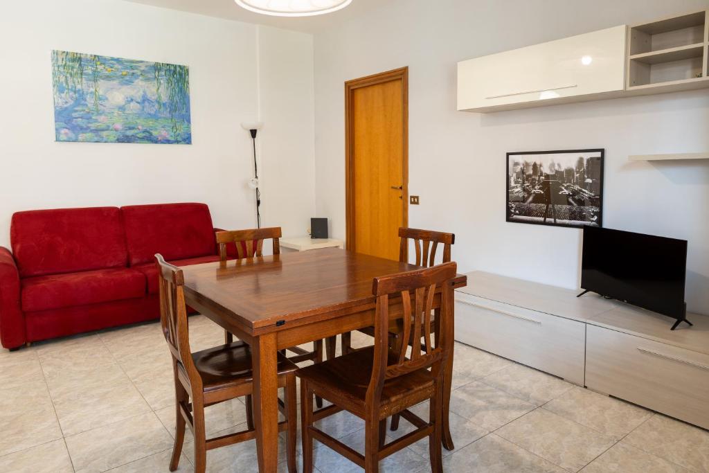 salon z drewnianym stołem i czerwoną kanapą w obiekcie Alessandrino Apartment w Rzymie