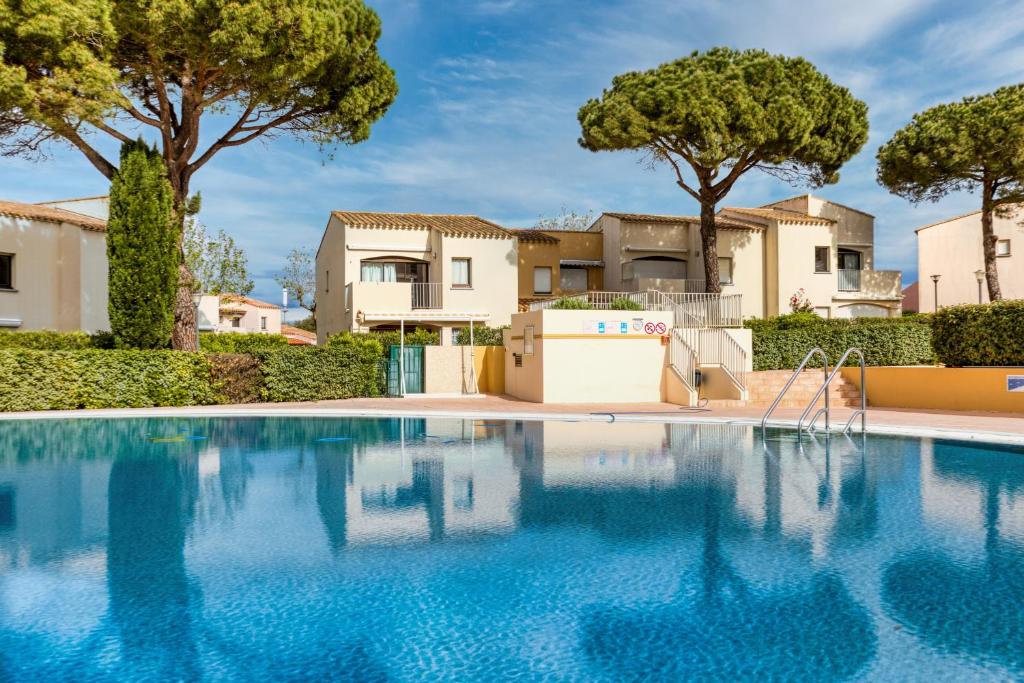 une piscine avec des arbres et des maisons en arrière-plan dans l'établissement Appartement Plain Pied Cap, au Cap d'Agde