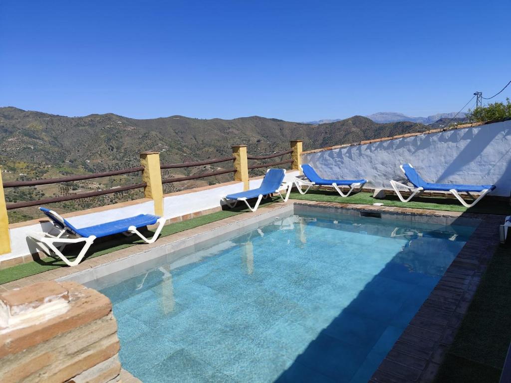 una piscina con 2 sillas azules junto a una valla en Casa Villazo II, en Almáchar