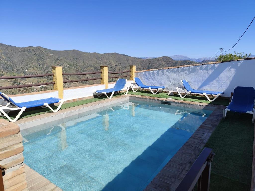 een zwembad met twee blauwe stoelen bij Casa Villazo II in Almáchar