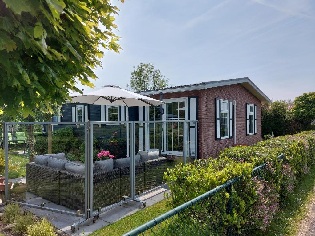 una casa con una sombrilla en un jardín en Schelde vakantie chalet, en Baarland
