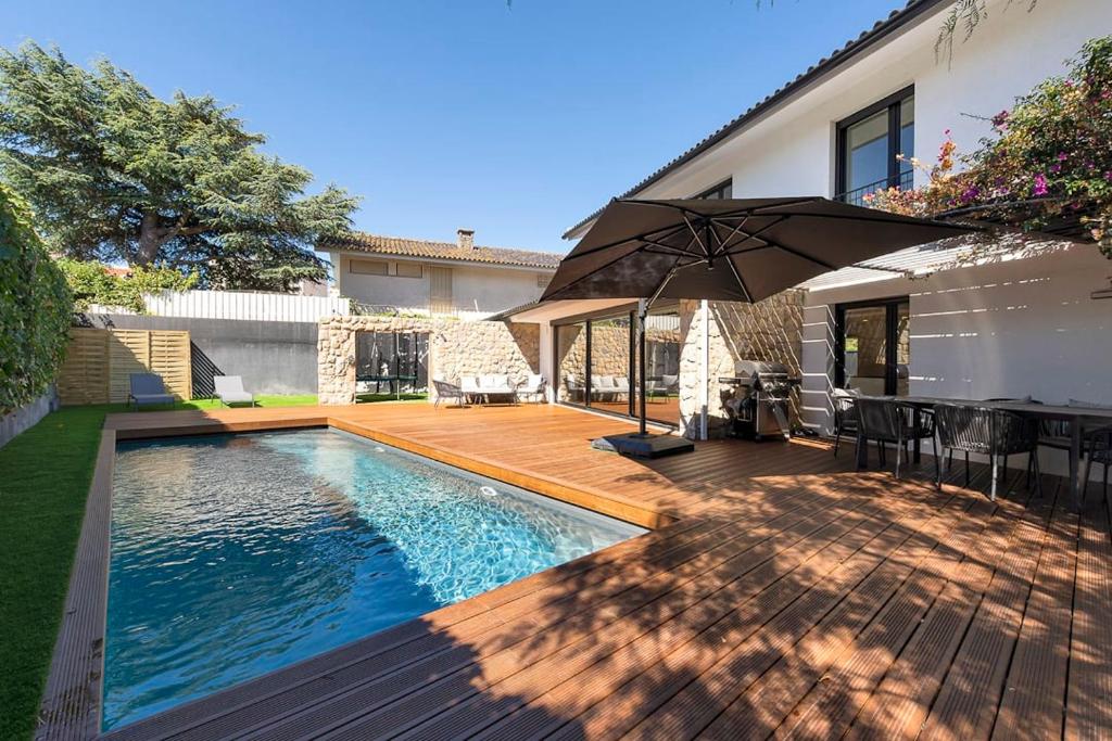 a swimming pool with an umbrella next to a house at Rosario Pool Villa in Cascais