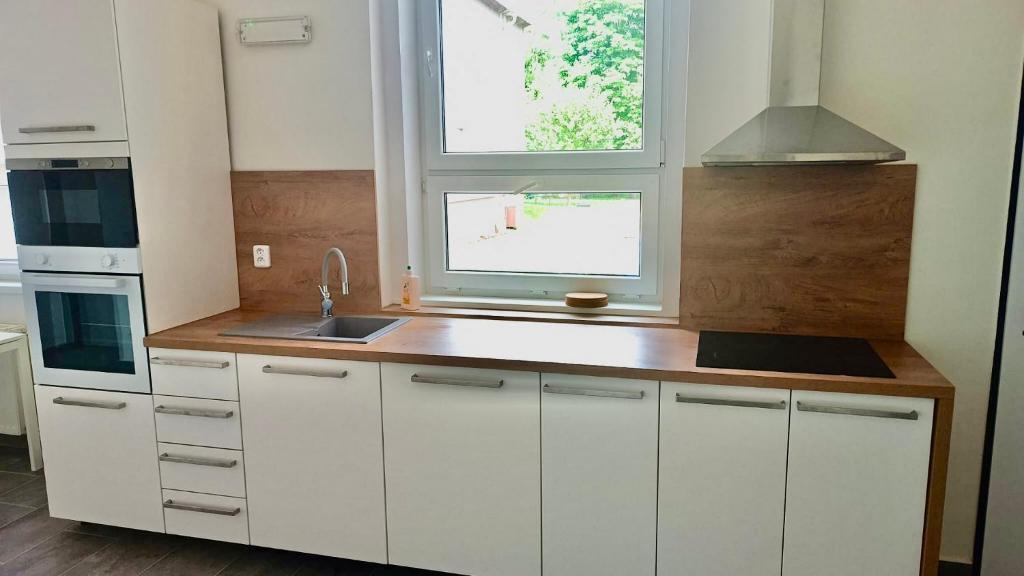 a kitchen with white cabinets and a sink and a window at Hotel Hangar in Mošnov