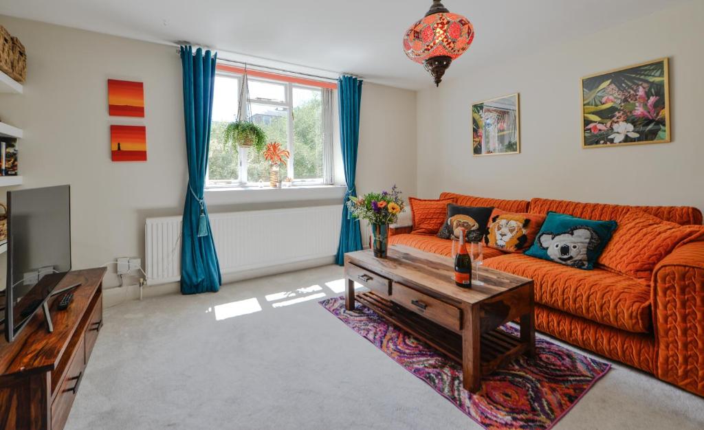 ein Wohnzimmer mit einem orangenen Sofa und einem Tisch in der Unterkunft Luxurious quirky flat in Greenwich O2 Arena with free parking in London