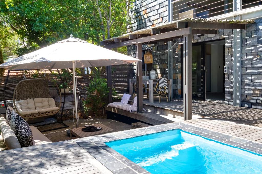 a swimming pool with an umbrella next to a building at Sweet Greta - Garden Apartment With Solar Power in Cape Town