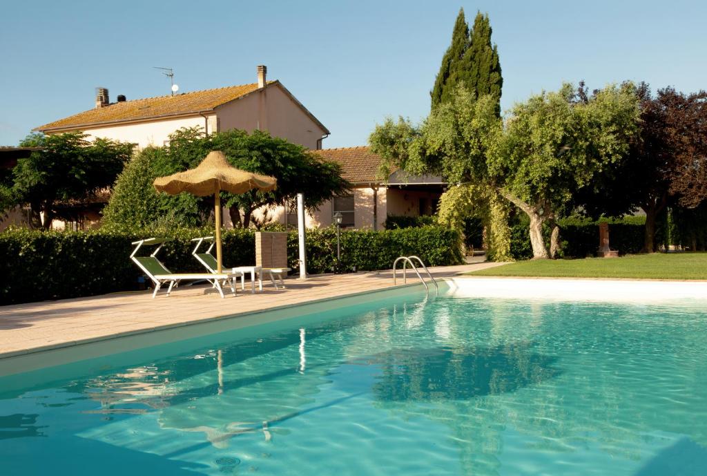 a swimming pool with two chairs and an umbrella at Agriturismo Al Vermigliano in Alberese
